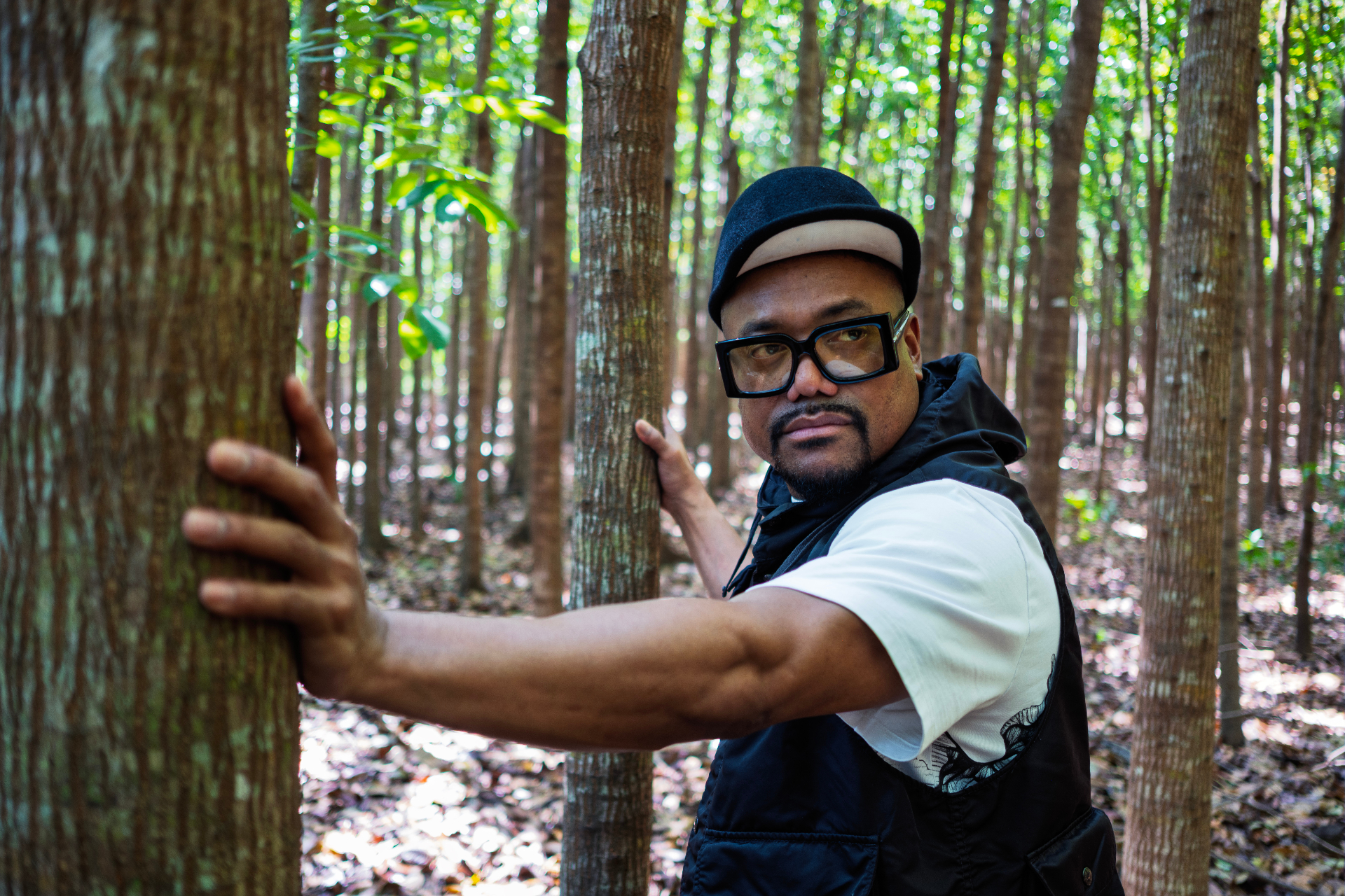 Portrait of Apl among tall, thin tree trunks in a forest.